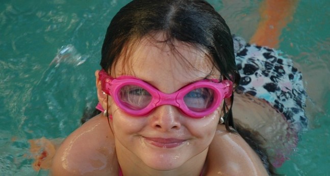 Child wearing pink goggles in pool